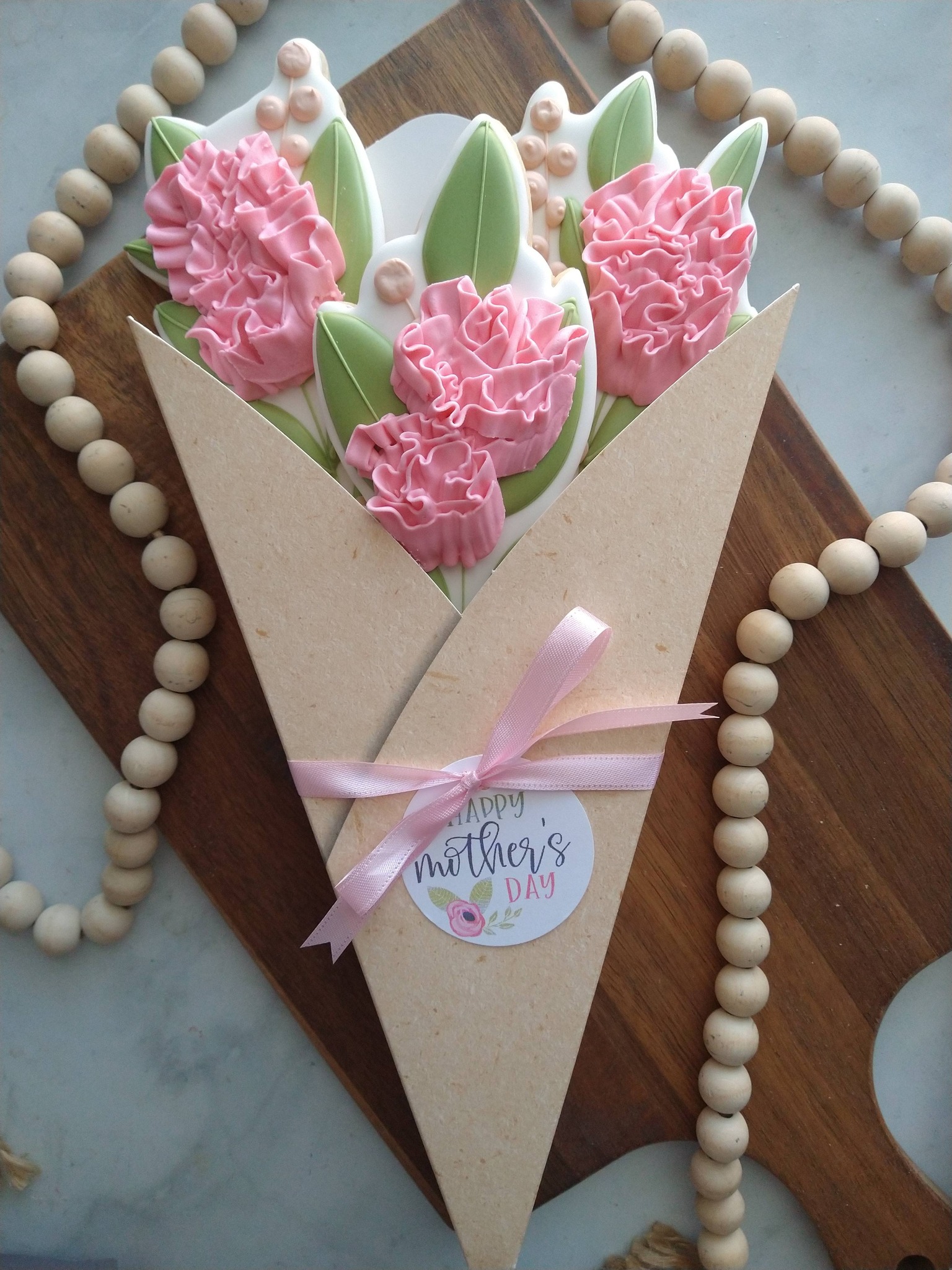 Mother’s Day cookie bouquet with pink flowers, leaves, and ribbon wrapping