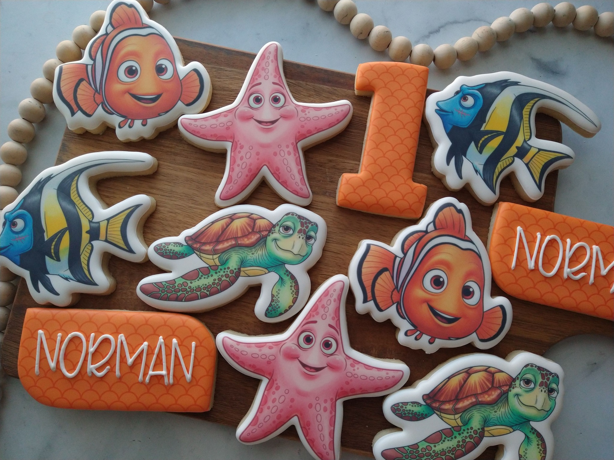 Ocean birthday cookies with fish, starfish, turtles, orange number one, and personalized name cookies